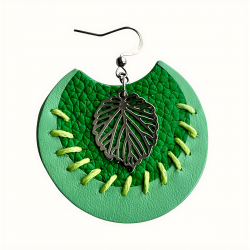 Gros plan sur boucles d'oreilles en cuir vert avec broderie