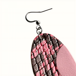 Gros plan sur la texture du cuir des boucles d'oreilles ovales rose en cuir