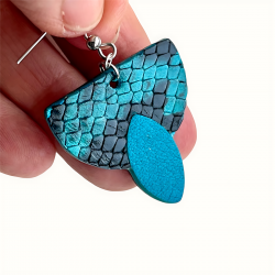 Gros plan sur boucle d'oreille en cuir bleu et noir effet reptile
