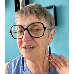 Boucles d'oreilles en cuir noir et acier inoxydable doré portées par une personne