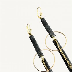 Gros plan sur les hauts de boucles d'oreilles en cuir noir et acier inoxydable doré