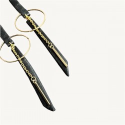 Gros plan sur le bas des boucles d'oreilles en cuir noir et acier inoxydable doré
